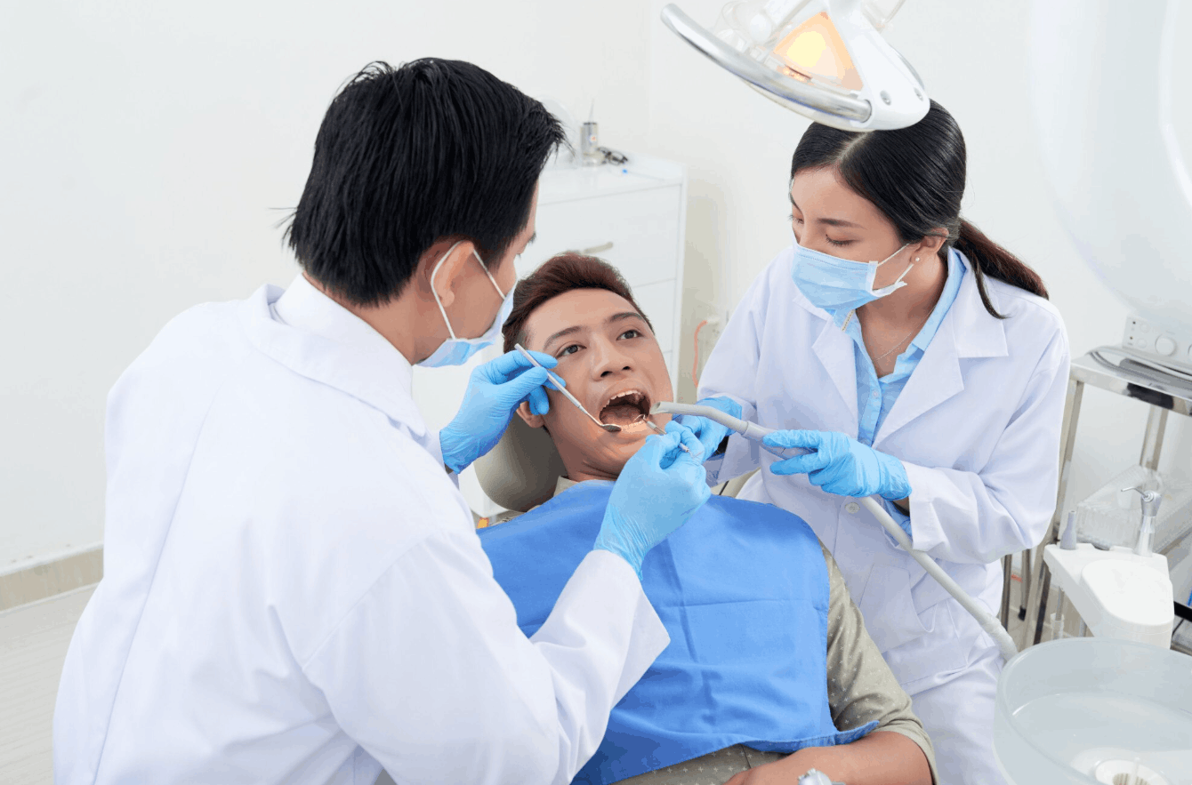 patient getting their teeth checked by the dentist assisted by a nurse