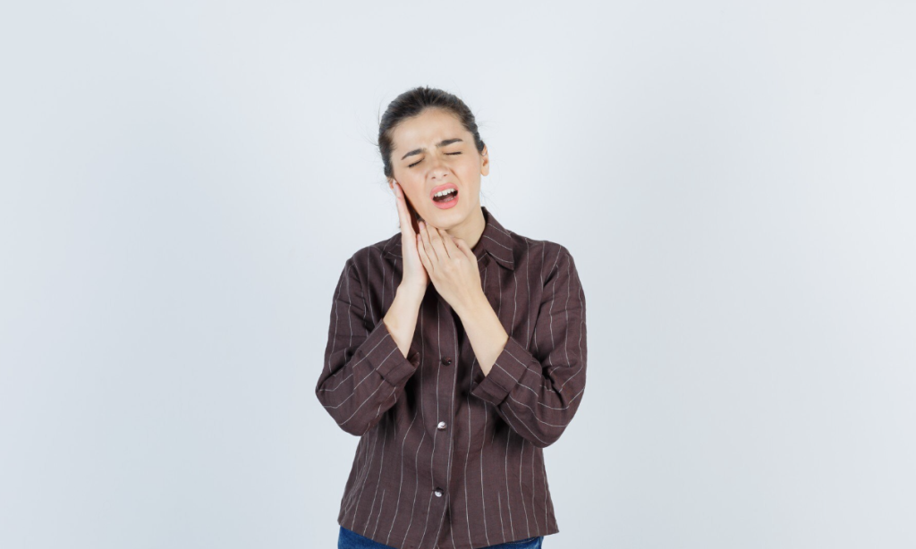 woman holding her right cheek in pain