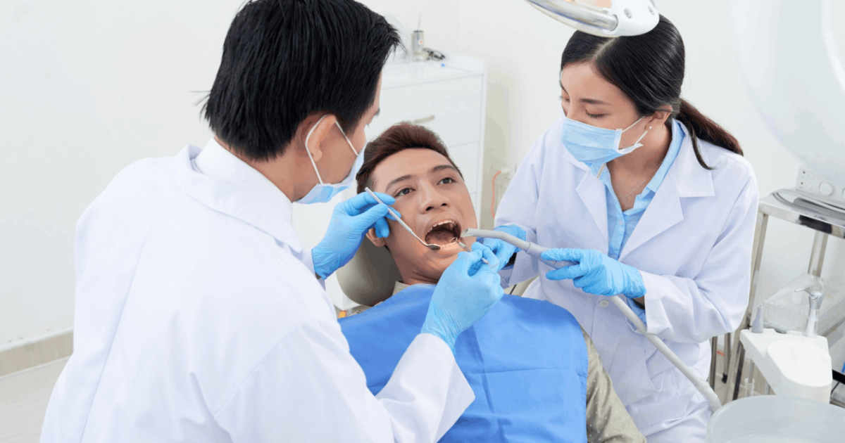 patient getting their teeth checked by the dentist assisted by a nurse